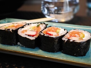 Sushi rolls arranged neatly on a blue plate with water in the background, creating a delightful dining moment