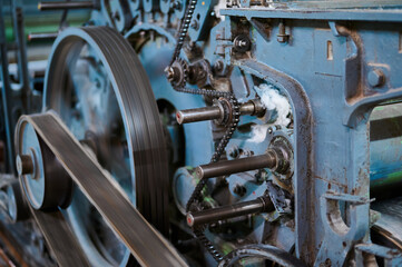 Exploring the intricate mechanisms of a vintage carding machine in a textile workshop showcasing...