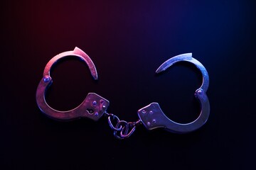 Open Handcuffs Under Neon Police Lights