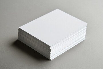 Stack of blank white paper arranged neatly on a gray surface in a well-lit space