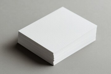 Stacked blank business cards resting on a minimalist gray surface in natural light for creative design ideas