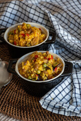 homemade dish of paella with vegetables in small casserole dish