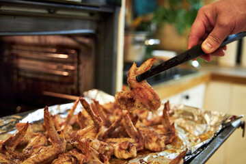 man cooks chicken wings in the oven