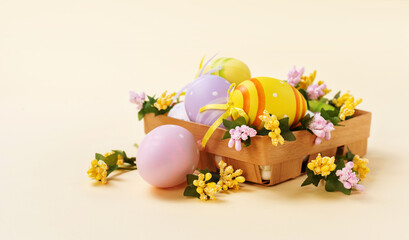 Easter basket with decorated colored eggs. Square basket with painted eggs and flowers on a pastel yellow background.