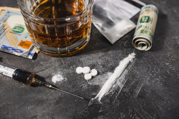 White narcotic pills, an alcoholic drink in a glass, a syringe with a dose of heroin, a line of...