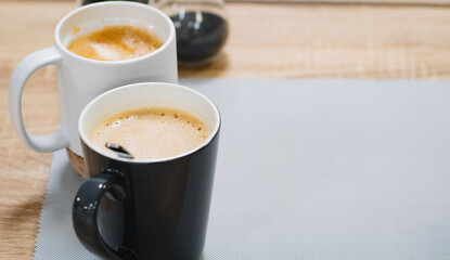 Side view of hot latte coffee  in a white cup and black cup on wooden table
