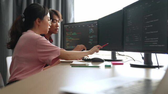 Slow motion back end software developer engineer for computer programming working together on debugging writing computing code, solving complex algorithms display on monitor in office. Burgeoning