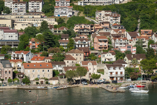 Bay of Kotor, Montenegro - July 2, 2024: Dobrota shoreline with small piers and boats. Resdential houses and smaller hotels and businesses