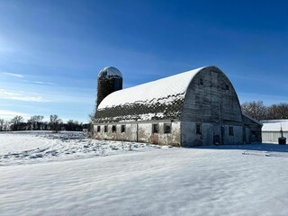 Old Round barn complete with silo in the rural snow covered countryside