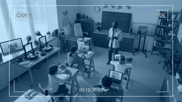 High angle camera shot of African American male teacher lecturing to elementary school children during 3D modelling class in modern school