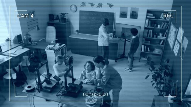 High angle camera shot of African American male teacher talking to his student near chalkboard and other children completing their task with 3D printer in modern school classroom