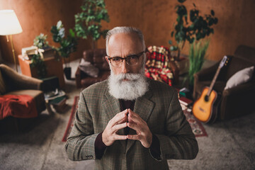 Elegant elderly man posing in retro-inspired living room with stylish suit and beard