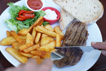 At the restaurant, beef steak, fried potatoes plate and bread