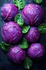 Fresh organic purple cabbage with green leaves on black surface