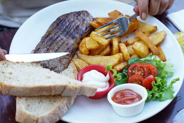 At the restaurant, beef steak, fried potatoes plate and bread
