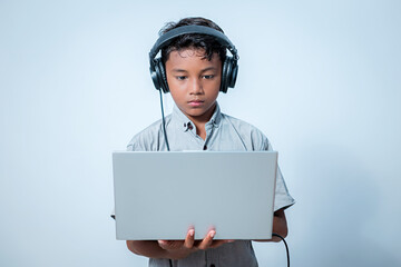 Boy is listening to something from laptop through headphones. Indonesian people