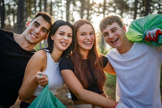 portrait of group of friends volunteers prepare to collect garbage waste and clean forest nature in summer day slow motion