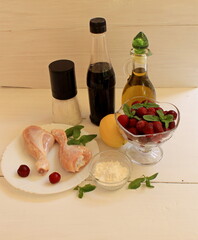 Baked chicken with lemon and mint on a plate. Ingredients for cooking chicken breast on a wooden background. Selective focus.
