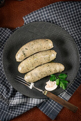 Three cooked white sausages on a plate.