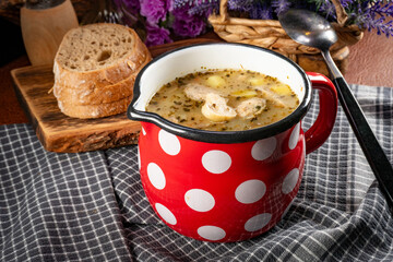Sour rye soup with pieces of white sausage and mushrooms.