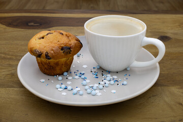 A plate of muffins and a cup of coffee sit on a table