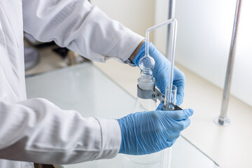 A female chemist assembles a device for distilling and absorbing arsenic in food products.