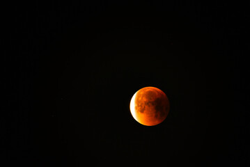 Close up of a glowing blood moon during a partial lunar eclipse at night.