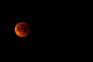 A glowing blood moon during a partial lunar eclipse at night.