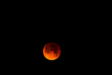 A glowing blood moon during a partial lunar eclipse at night.