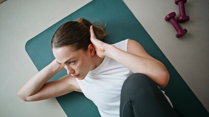 Woman performing sit-ups fitness mat indoors closeup top view. Energetic girl