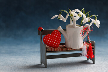 Card for the holiday of March 1, Martisor, Baba Marta. Decorative bench with a watering can, a bouquet of snowdrops, heart, red and white symbol of Martenitsa, copy space