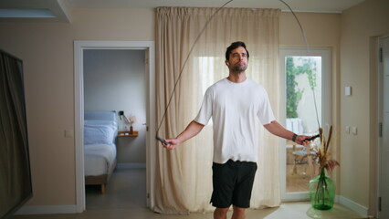 Energetic guy jumping rope with determination wearing wireless earphones.
