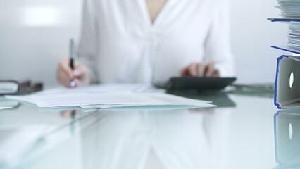 Binders of financial documents are lying on the glass table and waiting to process near the female...