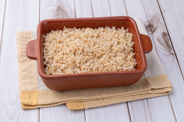 Cooked brown whole rice in a plate over wooden table