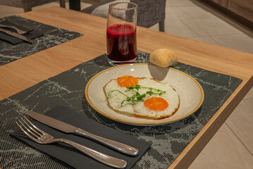Sunny-Side-Up Eggs with Bread and Juice on a Breakfast Table
