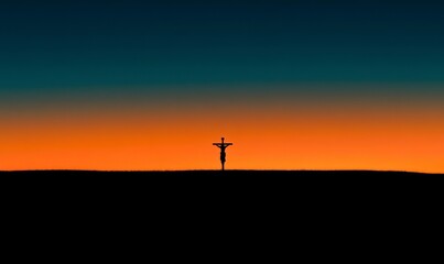 Silhouette of Jesus Christ on the cross against a sunset sky background, an Easter concept.