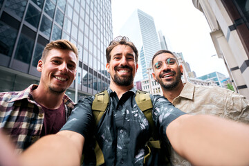 Three happy male tourists are taking a selfie with skyscrapers and modern buildings in the...