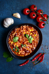 Chili con carne - traditional mexican minced meat and vegetables stew in tomato sauce in a cast iron pan. Top view with copy space.
