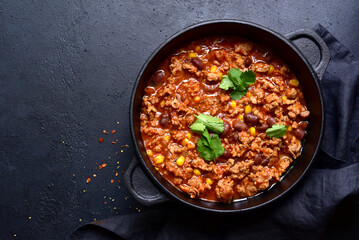 Chili con carne - traditional mexican minced meat and vegetables stew in tomato sauce in a cast iron pan. Top view with copy space.