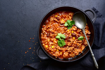 Chili con carne - traditional mexican minced meat and vegetables stew in tomato sauce in a cast iron pan. Top view with copy space.
