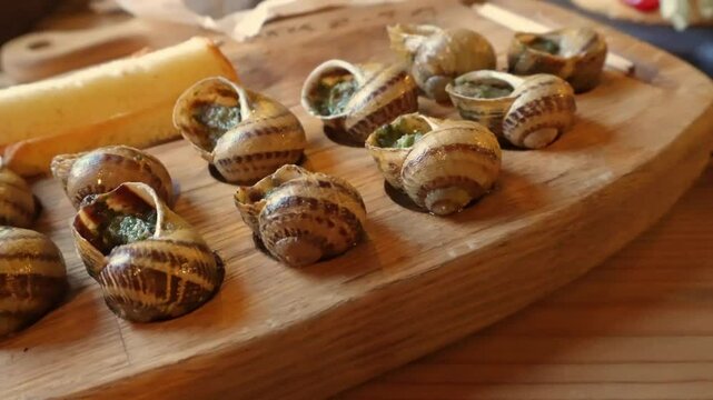 Freshly prepared escargot with garlic butter on wooden board in warm rustic setting