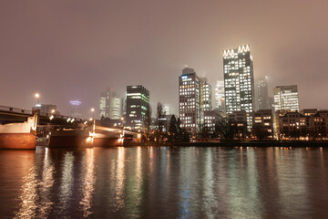 Fototapeta premium Modern cityscape with illuminated skyscrapers, bridge, and river at night