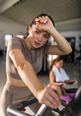 Woman working hard during indoor cycling session at gym