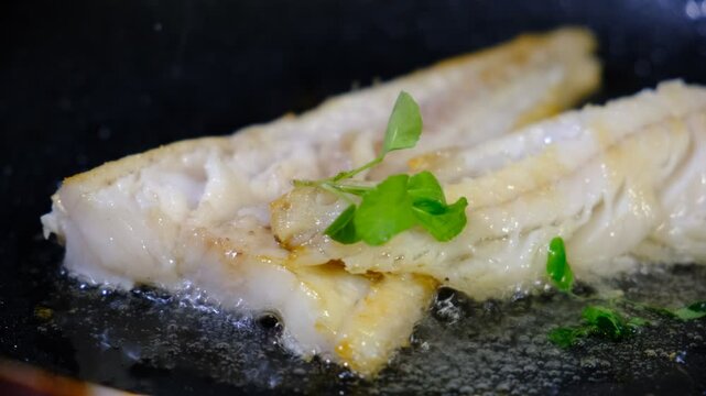 Cooking Indoors pan grilled seasoned Cod fillets on Stovetop, iron cast pan, close up boiled oil, deep fried. White meat