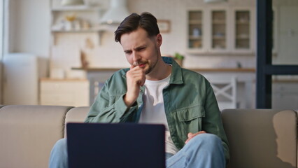 Sick man virtual chat using laptop at room sofa closeup. Serious guy coughing