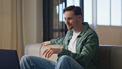 Happy hipster communicating laptop at couch closeup. Man talking video call