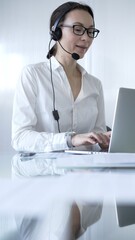 Female secretary wearing headset and working on laptop, providing customer support or online service. Business people concept