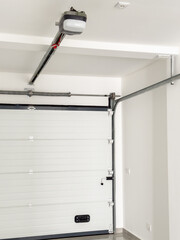 White automatic garage door with a motorized opener and metal support system.