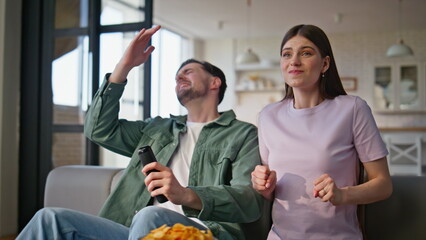 Sport fans watching TV expressing disappointment in room closeup. Pair football