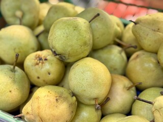 Pile of an ripe juicy pears in box on sale in vegetable stand display at supermarket show organic food, vegetarian food, healthy food
